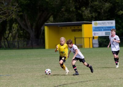 2 kids chasing after soccer ball